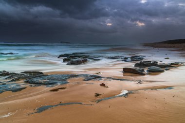 Avustralya, NSW 'nin merkez kıyısındaki Birdie Plajı' ndan deniz kenarında bulutlu bir güneş doğuyor..