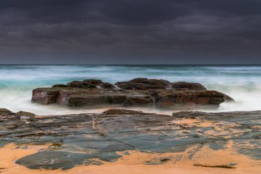 Avustralya, NSW 'nin merkez kıyısındaki Birdie Plajı' ndan deniz kenarında bulutlu bir güneş doğuyor..