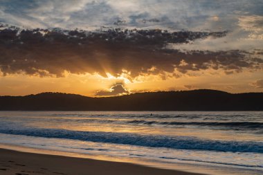 Gündoğumu renkleriyle kumsalda geçen sonbahar günleri Umina Sahili 'nde, NSW, Avustralya.