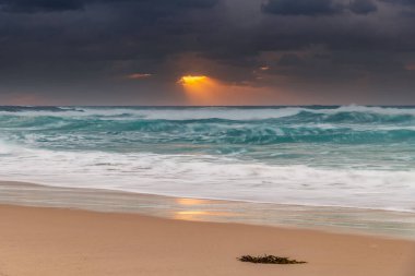 Avustralya, NSW 'nin merkez kıyısındaki Birdie Plajı' ndan deniz kenarında bulutlu bir güneş doğuyor..