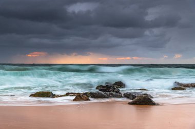 Yağmur bulutları gökyüzünü dolduruyor ve dalgalar hızla yükseliyor. Central Coast, NSW, Avustralya 'daki Killcare Sahili' nden gündoğumu deniz manzarası..