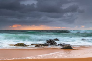 Yağmur bulutları gökyüzünü dolduruyor ve dalgalar hızla yükseliyor. Central Coast, NSW, Avustralya 'daki Killcare Sahili' nden gündoğumu deniz manzarası..