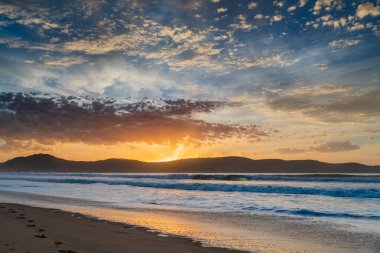 Gündoğumu renkleriyle kumsalda geçen sonbahar günleri Umina Sahili 'nde, NSW, Avustralya.