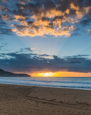 Gündoğumu gökyüzünü aydınlatıyor Killcare Sahili 'nden Central Coast, NSW, Avustralya.