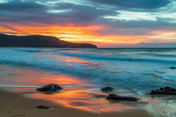Sunrise seascape with a mix of high and low cloud producing pretty skies at Killcare Beach on the Central Coast, NSW, Australia.