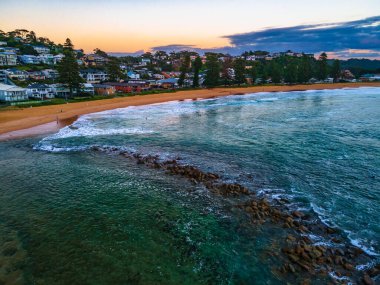 Central Coast, NSW, Avustralya 'daki Avoca Sahili' nde sörfçülerle yaz gündoğumu deniz manzarası.