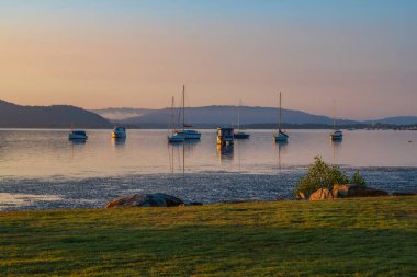 Central Coast, NSW, Avustralya 'daki Koolewong rıhtımında tekne ve yansımalarla güzel bir gün doğumu..