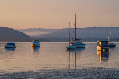 Central Coast, NSW, Avustralya 'daki Koolewong rıhtımında tekne ve yansımalarla güzel bir gün doğumu..