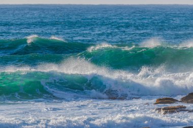 Sabahın erken saatlerinde Orta Sahildeki MacMasters Sahili 'nde 1,5 ila 2,5 metrelik dalgalarla sörf yapmak..