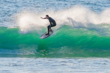 Sabahın erken saatlerinde Orta Sahildeki MacMasters Sahili 'nde 1,5 ila 2,5 metrelik dalgalarla sörf yapmak..
