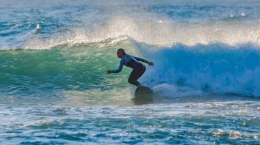 Sabahın erken saatlerinde Orta Sahildeki MacMasters Sahili 'nde 1,5 ila 2,5 metrelik dalgalarla sörf yapmak..