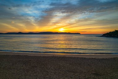 Sahil kenarında gün doğumu bulutlu gökyüzü Pearl Beach 'ten Central Coast, NSW, Avustralya.