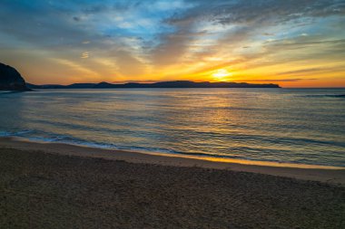 Sahil kenarında gün doğumu bulutlu gökyüzü Pearl Beach 'ten Central Coast, NSW, Avustralya.