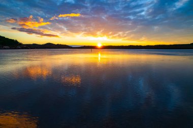 Orta ve yüksek bulut örtüsü karışımlı hava gündoğumu su manzarası Orta Sahilde, NSW, Avustralya 'da Woy Woy körfezindeki suya yansıyor.