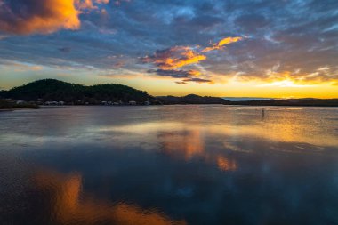 Orta ve yüksek bulut örtüsü karışımlı hava gündoğumu su manzarası Orta Sahilde, NSW, Avustralya 'da Woy Woy körfezindeki suya yansıyor.