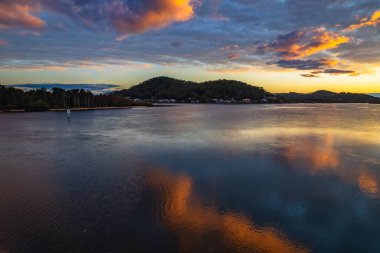 Orta ve yüksek bulut örtüsü karışımlı hava gündoğumu su manzarası Orta Sahilde, NSW, Avustralya 'da Woy Woy körfezindeki suya yansıyor.