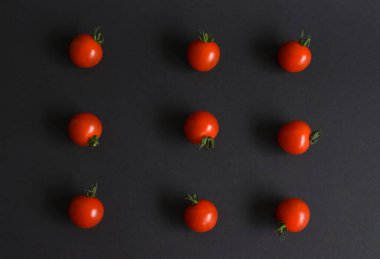 Koyu arkaplanda kırmızı domates deseni var. Düz yatış, üst görünüm.