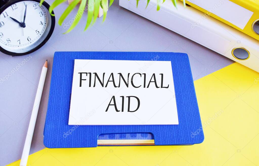 Financial Aid text written on whie paper above on Notebook, Business concept to illustrate official help given to a person, organization, or country in the form of money, loans, reduced taxes, etc.