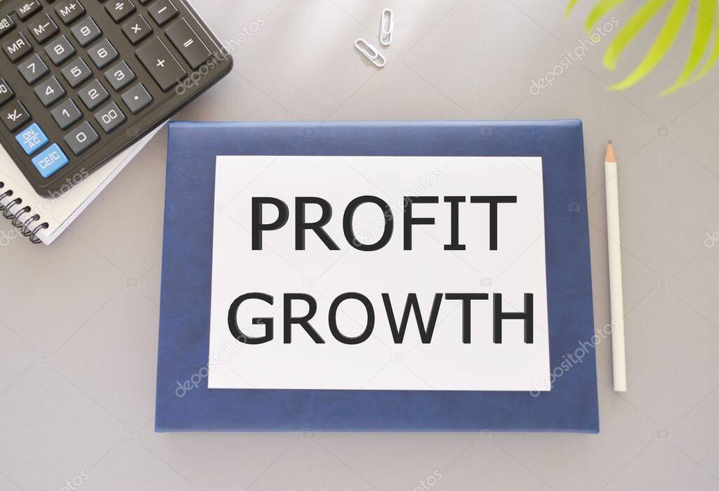 Profit growth text written on white paper above on Notebook. Concept of business success in investment or company revenue more than expense.