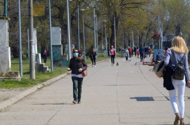 Sırbistan, Belgrad, 04.04.2020: Güneşli bir günde yürüyen insanlar, Corona virüsüne karşı koruma amaçlı tıbbi maske takıyor