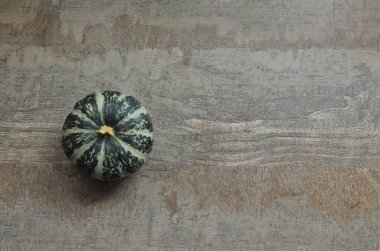 Minimum Sonbahar konsepti: ahşap bir kırsal arka planda yeşil bir balkabağı