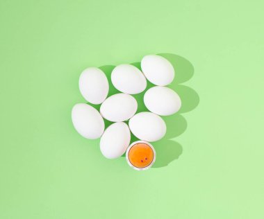 2021 Paskalyası, asgari yaratıcı kavram. Beyaz yumurtalar ve yumurta sarısı kırılmış, pastel yeşil arka planda. Yaratıcı düz yatak. Durgun yaşam bileşimi.