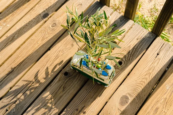 An old camper van transporting olive branches on the roof while crossing a wooden bridge. Summer travel in Greece concept.