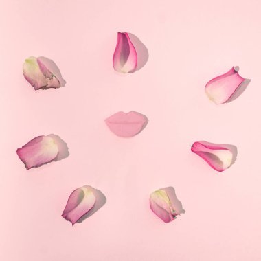Pastel pembe arka planda çıplak pembe dudaklar ve pembe gül yaprakları. Romantik aşk pastel konsepti ya da pembe güneşli yaratıcı gün tasarımı.