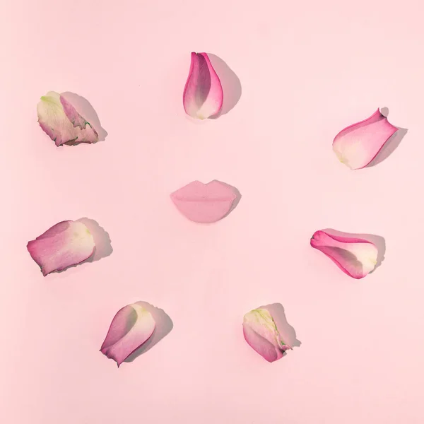 Pastel pembe arka planda çıplak pembe dudaklar ve pembe gül yaprakları. Romantik aşk pastel konsepti ya da pembe güneşli yaratıcı gün tasarımı.