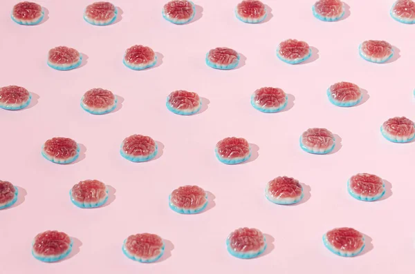 A pattern made of jelly beans in form of human brain on pastel pink background. The power of knowledge or human brain in action creative concept. Back to school and learning artistic design.