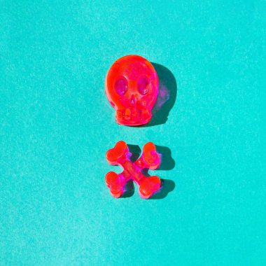 Bir kafatası ve pastel yeşil arka planda neon pembeli iki kemikten oluşan bir tehlike işareti. Cadılar Bayramı ürkütücü konsepti. Yeni retro Tehlike, dikkatli ol yaratıcı tasarım.