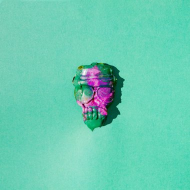 Yeşil ve mor boyalı bir kafatası. Ürkütücü bir kavram. Cadılar Bayramı yaratıcı tasarımı. Geçmişe dönük gelecek arka plan.