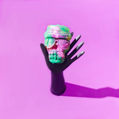 Ürkütücü renkli bir kafatasını tutan siyah bir el. Cadılar Bayramı 2021 korku konsepti.