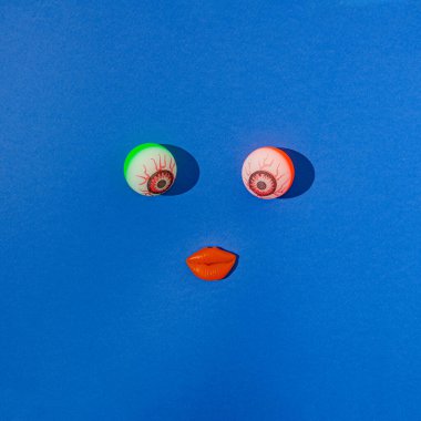 İki ürkütücü yuvarlanan göz ve mavi arka planda kırmızı dudaklar. Komik Cadılar Bayramı 2021 yaratıcı kavram