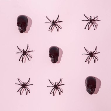 Siyah örümceklerden ve pastel pembe arka plandaki heykellerden oluşan bir desen. Korkunç Cadılar Bayramı yaratıcı konsepti. Parti daveti veya pankart tasarımı.