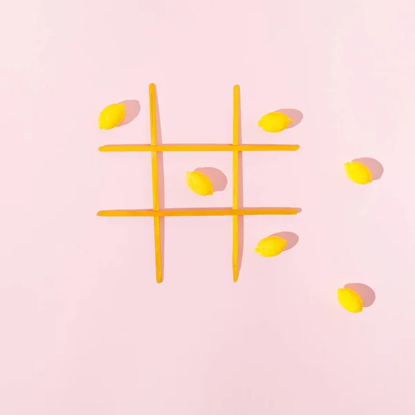 Pastel pembe arka planda limonlu bir tic tac toe oyunu. Parlak sarı Yazın yaratıcı konsepti.
