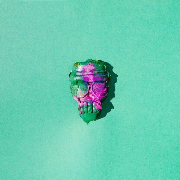 Yeşil ve mor boyalı bir kafatası. Ürkütücü bir kavram. Cadılar Bayramı yaratıcı tasarımı. Geçmişe dönük gelecek arka plan.