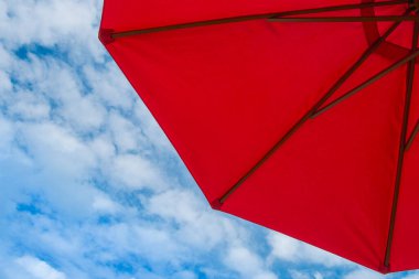 Mavi gökyüzü ve parlak atmosferi olan kırmızı şemsiye