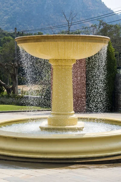 A large beautiful fountain in the middle of nature which is a good resting place.