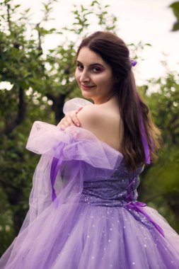 Arkadan bir kızın portresi. Mor elbiseli, korseli.