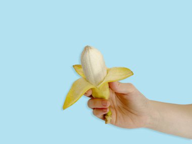 Muz kabuğu soyulmuş, mavi arka planda izole edilmiş.