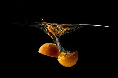 Su içinde siyah arka plan üzerine düşen turuncu