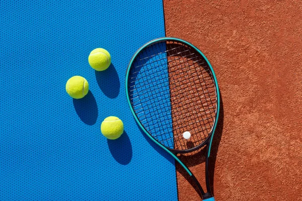 レッドクレイコートとブルージムマットのテニスラケットとボール テニス アクティブゲーム レジャー 健康的なライフスタイルの面白い概念 スポーツの背景 テキストのコピースペース — ストック写真