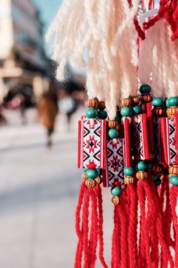 Bulgaristan 'ın Filibe kentinde Martenitsa ve bulanık cadde. Beyaz ve kırmızı işlemeli ulusal desenli geleneksel Bulgar mücevherleri. 1 Mart ilkbaharı konsepti