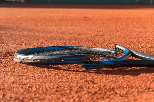 Kil tenis kortunda kırık tenis raketi. Sporda akıl sağlığı sorunu. Olumsuz duygular, stres, tatminsizlik, yenilgi, çöküş, başarısızlık, kayıp konsepti. Seçici odak