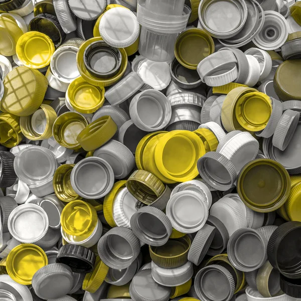 Yellow and gray single use plastic bottles caps are collection for recycling. Recycling plastic, ecology, waste management concept. Square background