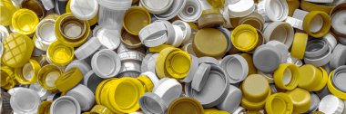 Sarı ve gri tek kullanımlı plastik şişe kapakları geri dönüşüm için toplanır. Plastik geri dönüşüm, ekoloji, atık yönetimi kavramı. Geçmişi. Geniş pankart