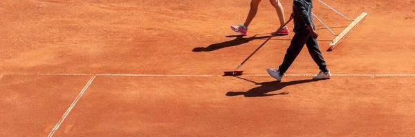 Maçtan sonra kil tenis kortu temizliği. Turuncu spor sahasının bakım ve hazırlık yüzeyi oyun için. Panoramik spor arka planı, geniş pankart, kopyalama alanı
