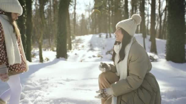 Piano intermedio. Figlia bacia mamma nella foresta innevata. Vista laterale. — Video Stock