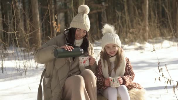 Piano intermedio. La mamma versa il tè caldo a sua figlia da un thermos. — Video Stock